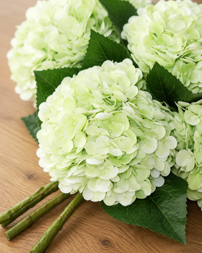 Close-up detail of the pale green artificial hydrangea bouquet on an oak table