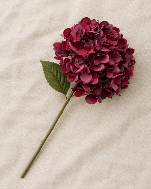 Burgundy Artificial Hydrangea Stem, shown alone on a linen background