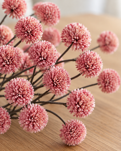 Close-up detail of the rose pink artificial chrysanthemum ball spray on an oak table