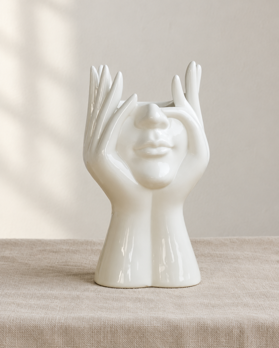 White Glossy Face and Hands Sculptural Vase, shown alone on a linen background