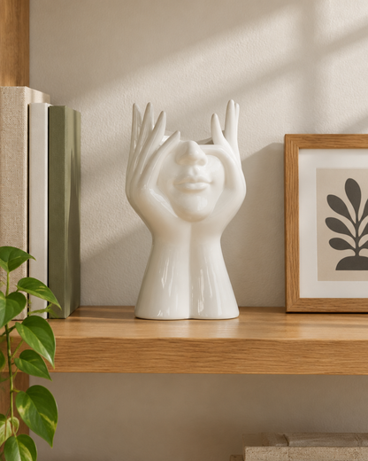 White Glossy Face and Hands Sculptural Vase on a wooden shelf