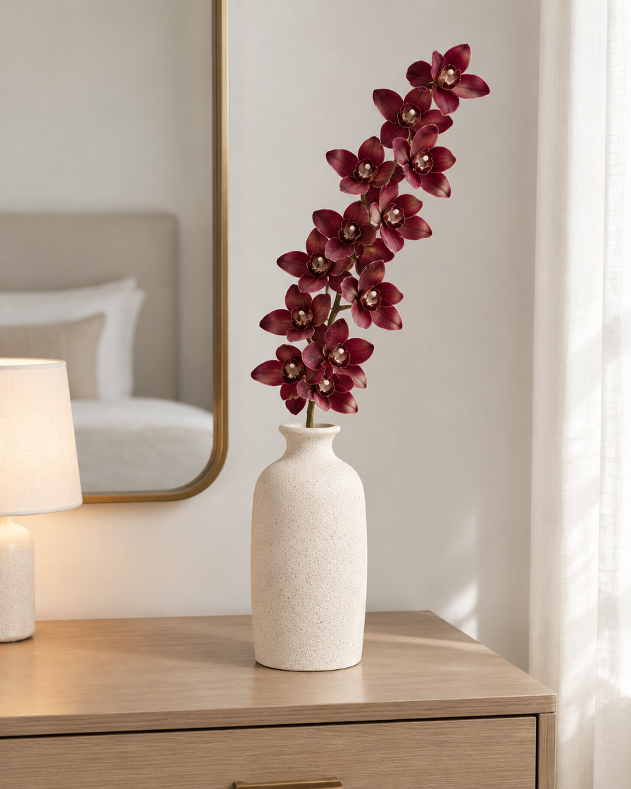 Burgundy Artificial Cymbidium Orchid Stem styled in a ceramic vase on a dresser (vase sold separately)