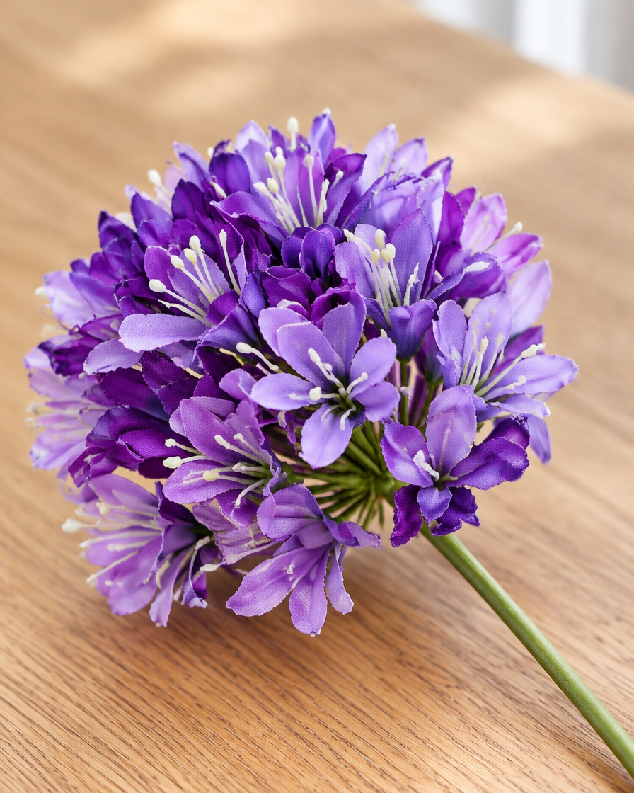 Close-up detail of the purple artificial agapanthus stem on an oak table